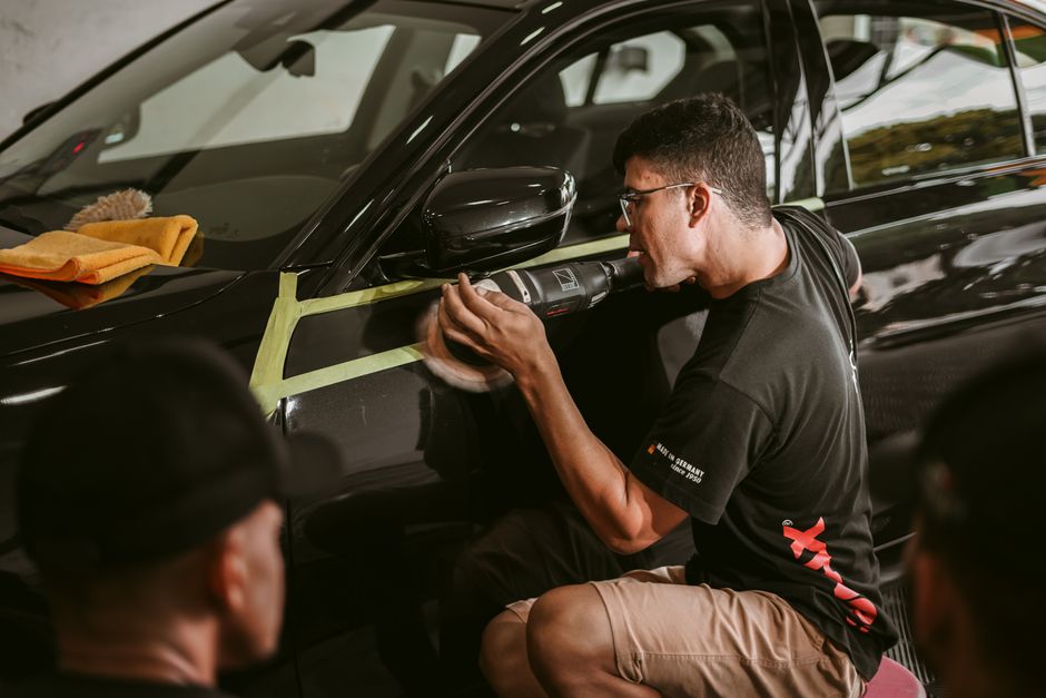 Professional auto detailer meticulously working on a vehicle exterior